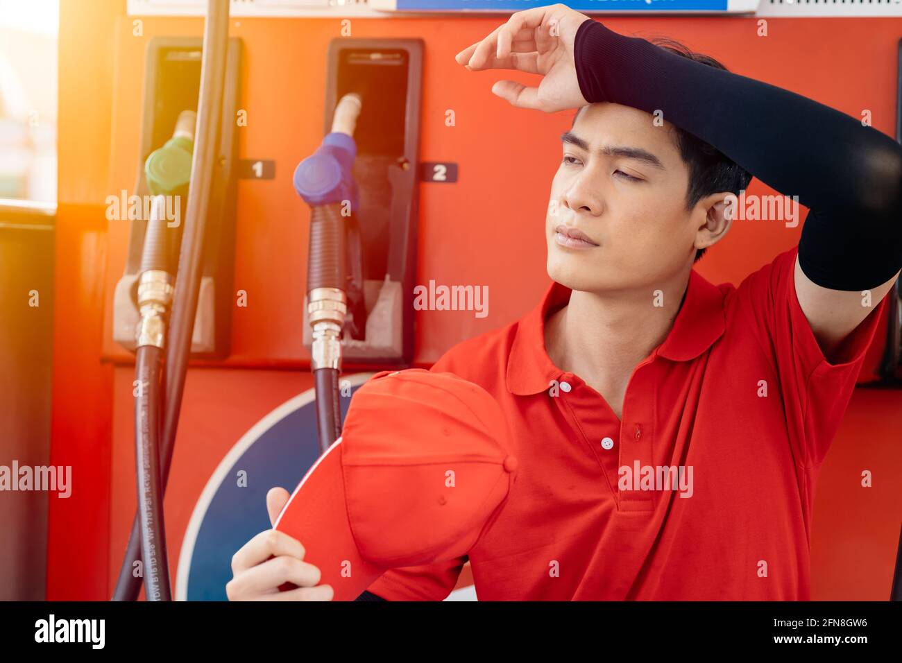 Un employé fatigué travaillant à la station-service se sent stressé pas de client et temps chaud en été Banque D'Images