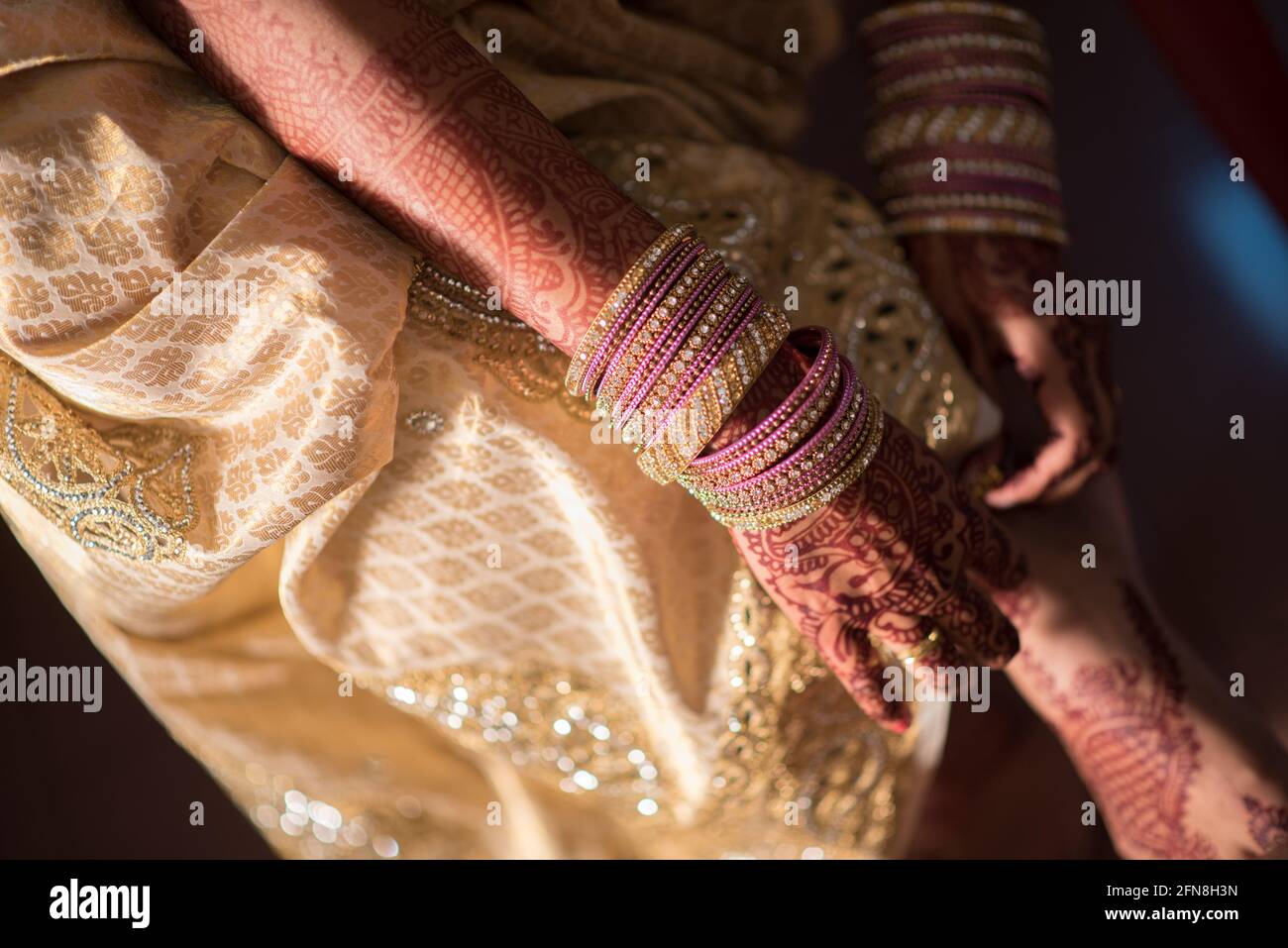 Mains avec des bracelets et tatouages de henné corrigeant l'ourlet de la robe Banque D'Images
