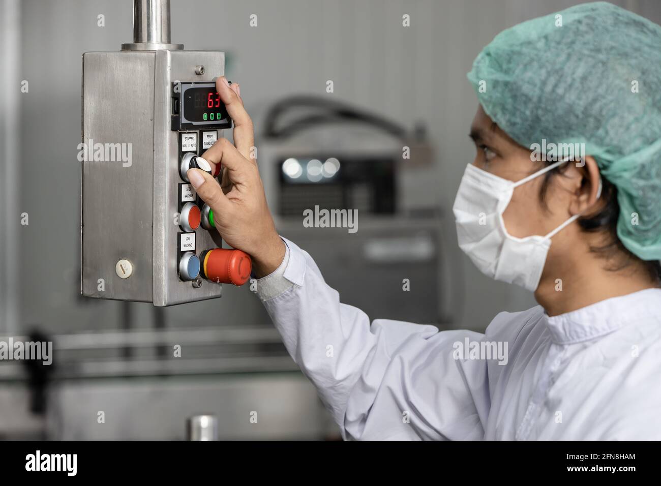 Les employés qui travaillent utilisent la machine de contrôle dans l'usine alimentaire d'hygiène. Banque D'Images