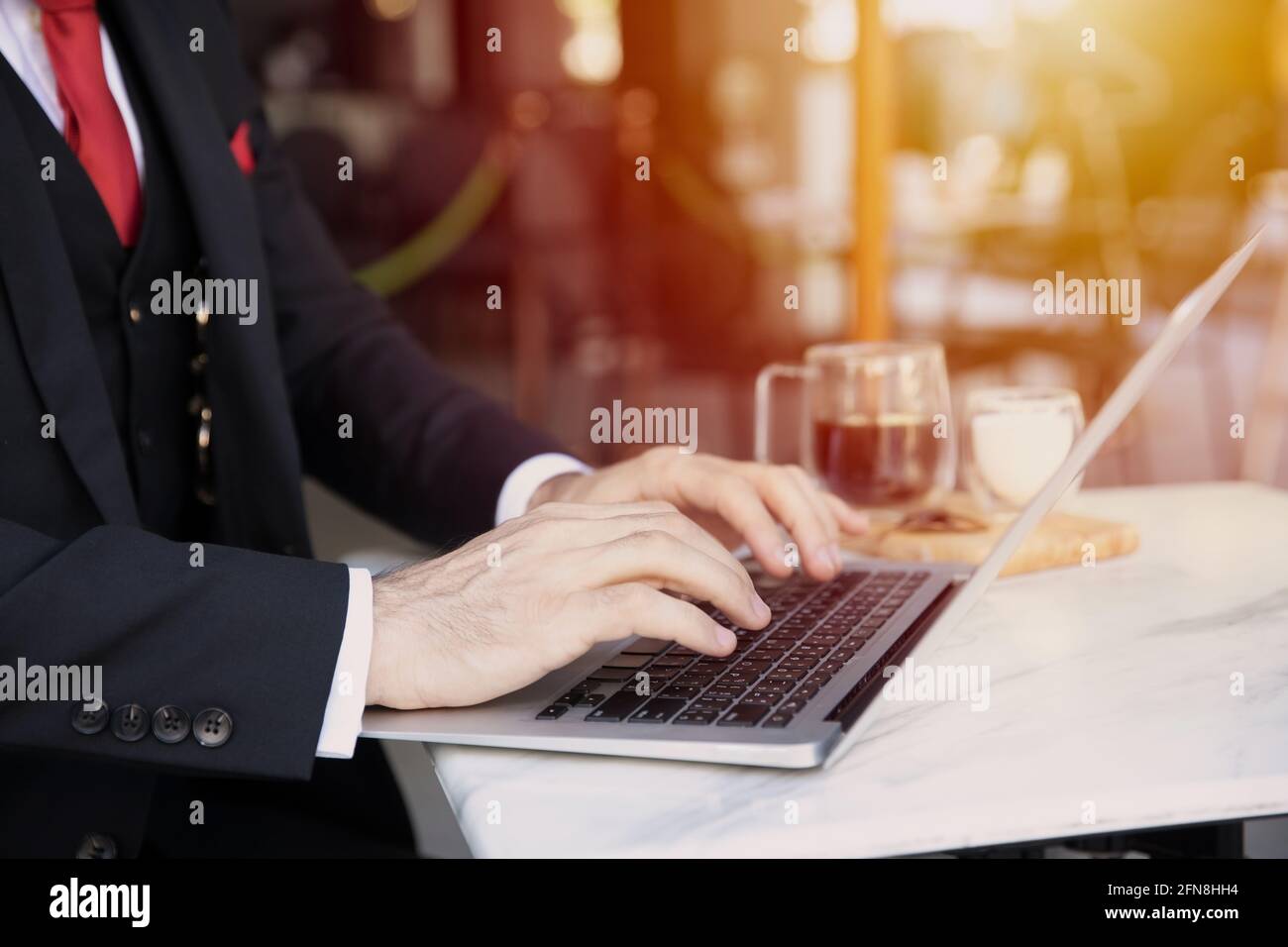 Homme d'affaires travaillant au café, homme d'affaires tapant sur un ordinateur portable avec du café sur la table. Banque D'Images