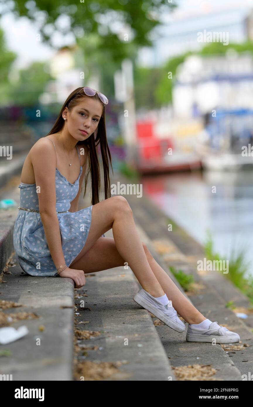 Portrait d'une jolie jeune femme prise en été dans une ville assise sur un escalier à côté d'une rivière. Banque D'Images