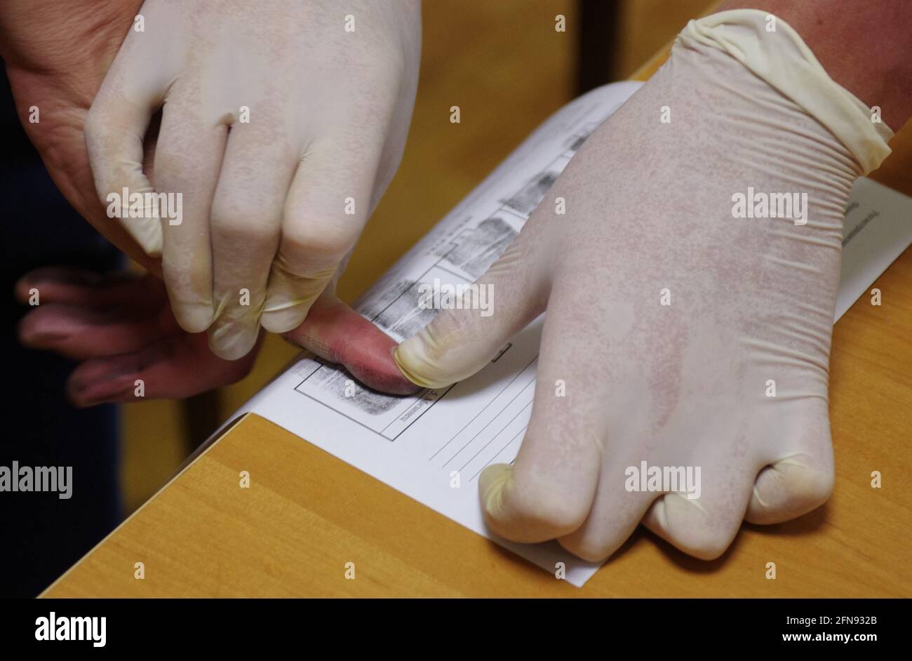 Un policier portant des gants en caoutchouc prend une empreinte digitale  d'un suspect Photo Stock - Alamy