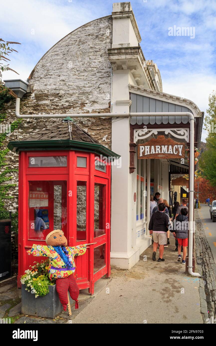 La ville historique d'Arrowtown, en Nouvelle-Zélande. Une pharmacie dans un bâtiment du XIXe siècle avec une ancienne cabine téléphonique rouge à l'extérieur Banque D'Images