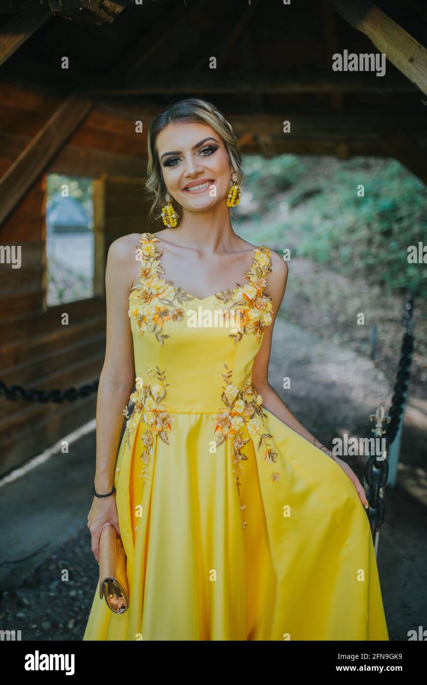 Magnifique femme blonde dans une élégante robe jaune posant ensuite à un  abri en bois Photo Stock - Alamy