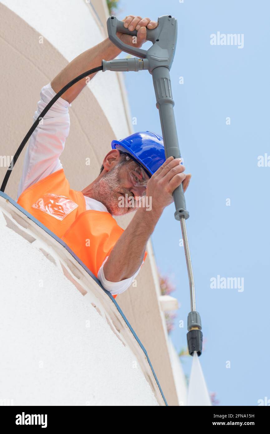 Homme nettoyant un mur de balcon à l'aide d'un nettoyeur haute pression  Photo Stock - Alamy