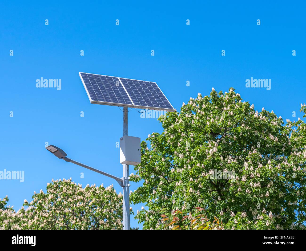 Une lampe de rue et un panneau solaire contre un ciel bleu. Banque D'Images