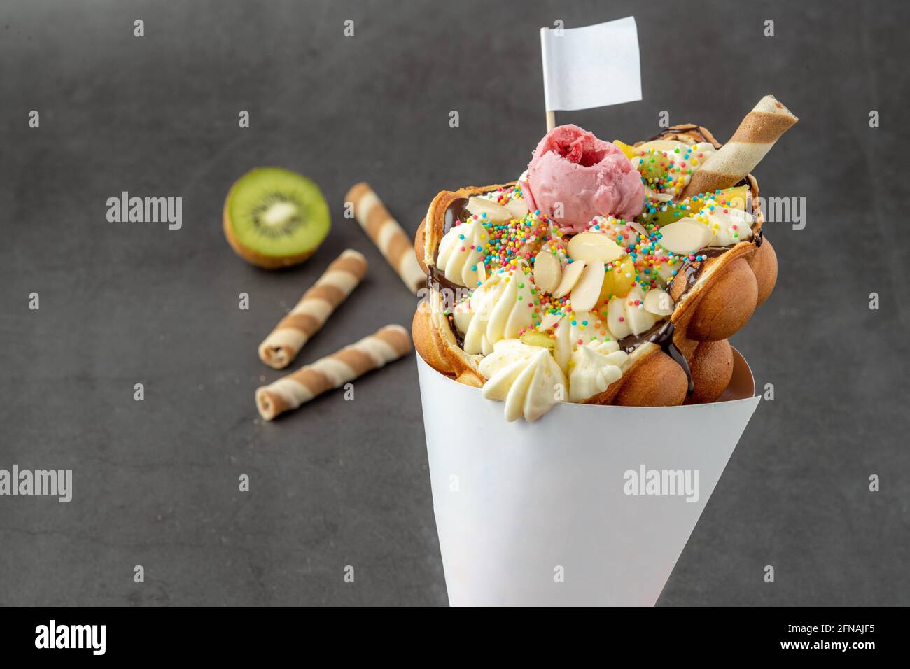 Hong kong ou gaufre à bulles avec crème glacée, fruits, sauce au chocolat et bonbons colorés Banque D'Images