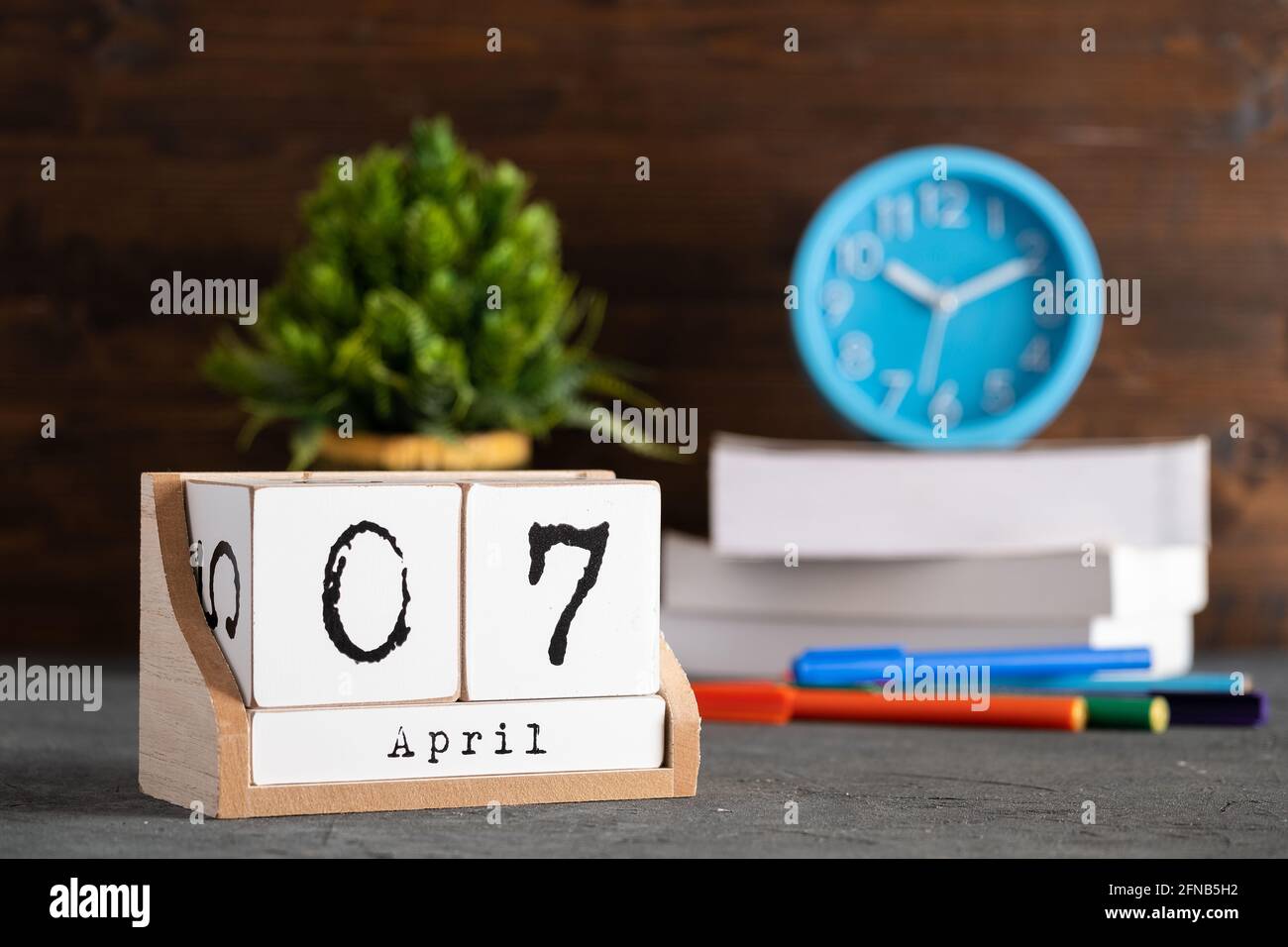7 avril. Avril 07 calendrier cube en bois avec objets flous sur fond. Banque D'Images