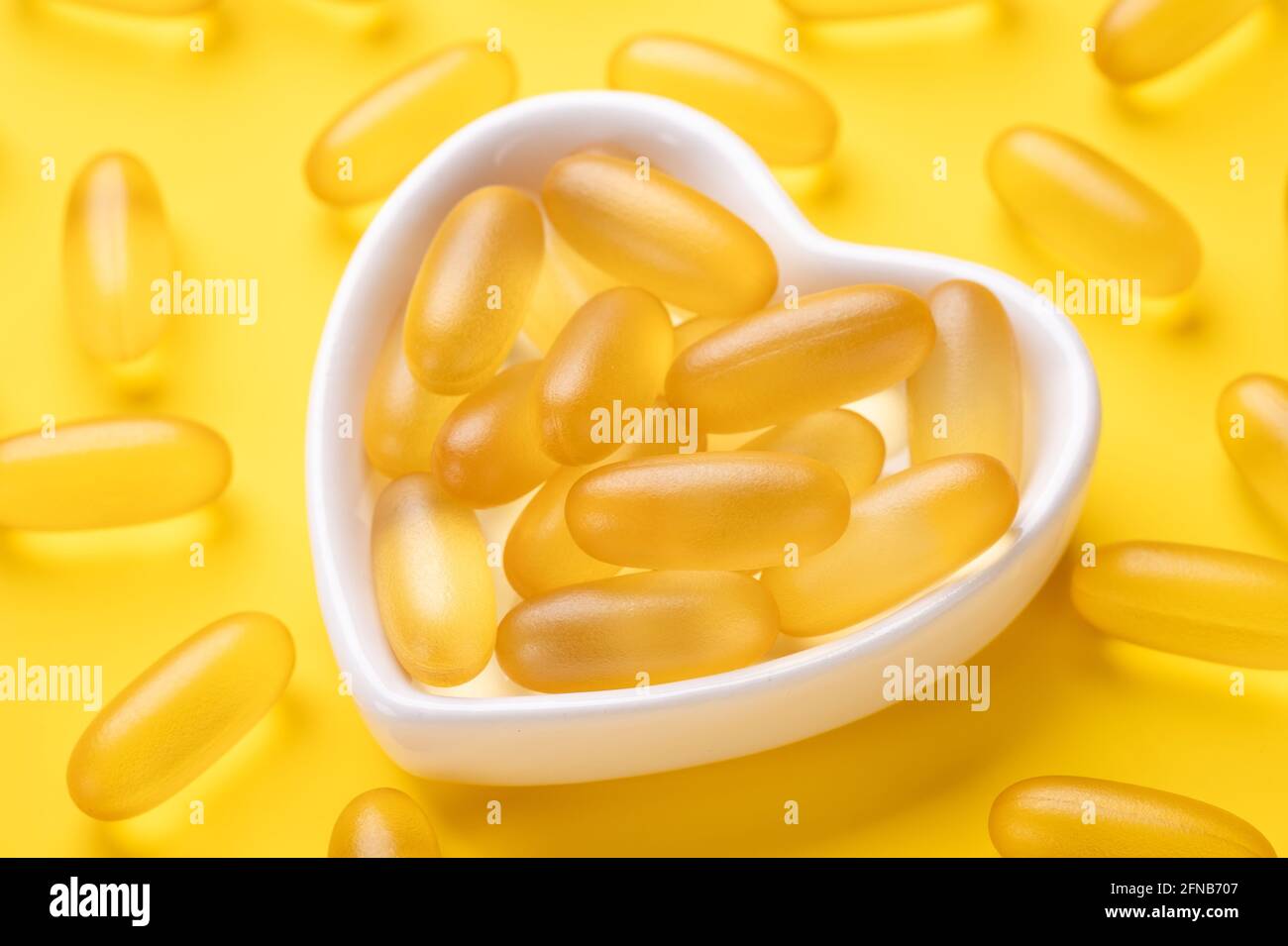 Fermez les capsules Omega 3 dans une plaque en forme de cœur sur fond jaune. Gels à base d'huile de poisson. Concept de soins de santé. Copier l'espace. Vue de dessus - image Banque D'Images