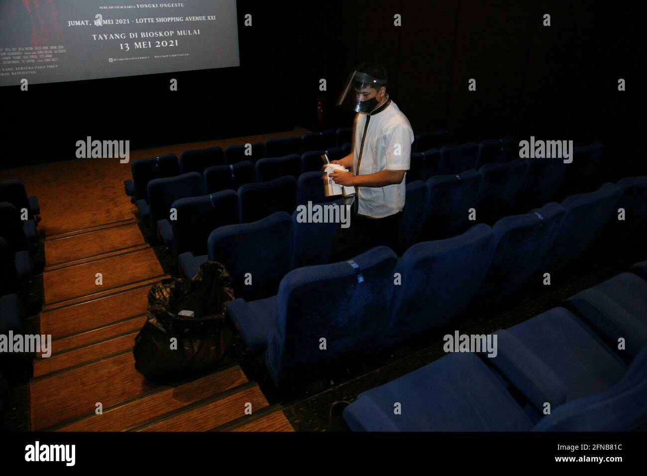 Le personnel du cinéma porte des masques et des écrans faciaux lors du nettoyage des sièges vides dans le XXI Cinema Theatre, dans la région de Kuningan, à Jakarta, le deuxième jour de la fête de l'Eid 2021 le vendredi 14 mai, 2021.l'application de protocoles de santé stricts dans les salles de cinéma peut réduire les inquiétudes au sujet du risque d'être exposé au virus corona. Le fait de regarder des films dans les salles de cinéma devrait être en mesure de redonner l'expérience passionnante de regarder sur grand écran au milieu d'une pandémie. (Photo de Kuncoro Widyo Rumpoko/Pacific Press) Banque D'Images