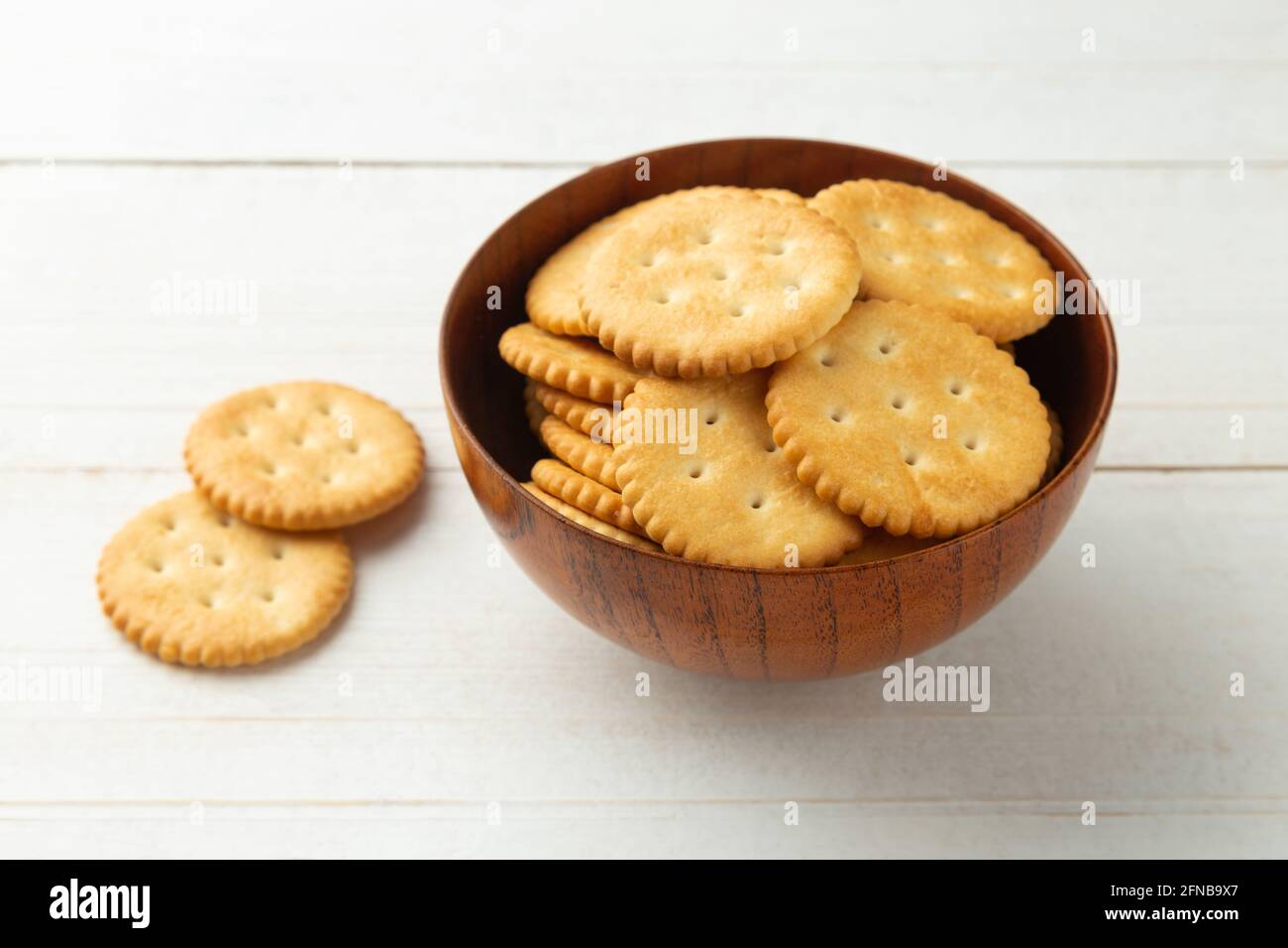 Biscuits craquelins arrondis dans un bol en bois sur fond de table en bois blanc. Banque D'Images Biscuits craquelins arrondis dans un bol en bois sur fond de table en bois blanc. Banque D'Images