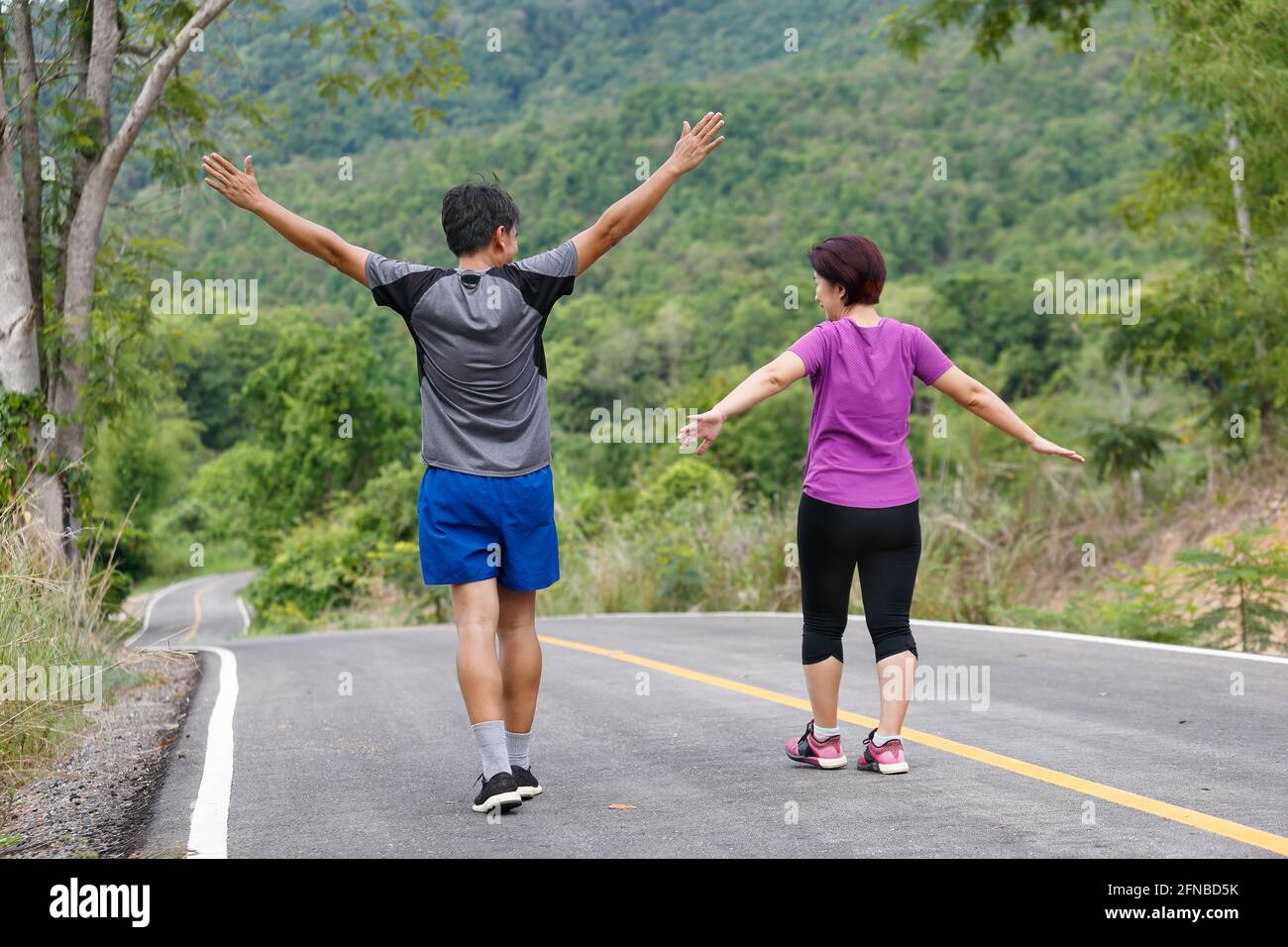 Un couple asiatique d'âge moyen s'étire les muscles avant de faire du jogging dans le parc Banque D'Images