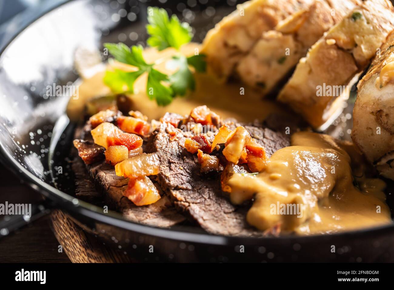 Un svickova typique de la cuisine tchèque avec des tranches de bœuf, une sauce à la crème, des boulettes de pain et des cubes de bacon frits. Banque D'Images