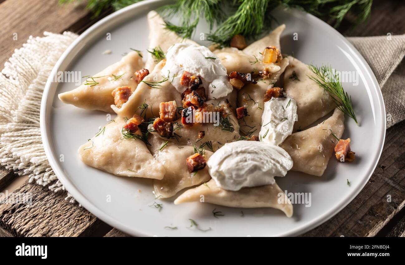 Pierogi traditionnel polonais, ukrainien ou slovaque avec crème aigre, bacon et aneth. Banque D'Images