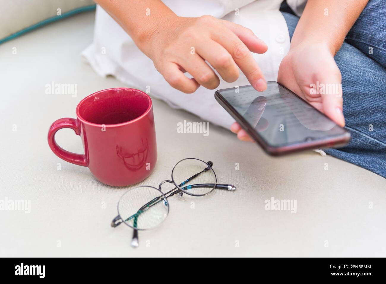 mains de femmes tenant un smartphone. tasse et verre Banque D'Images