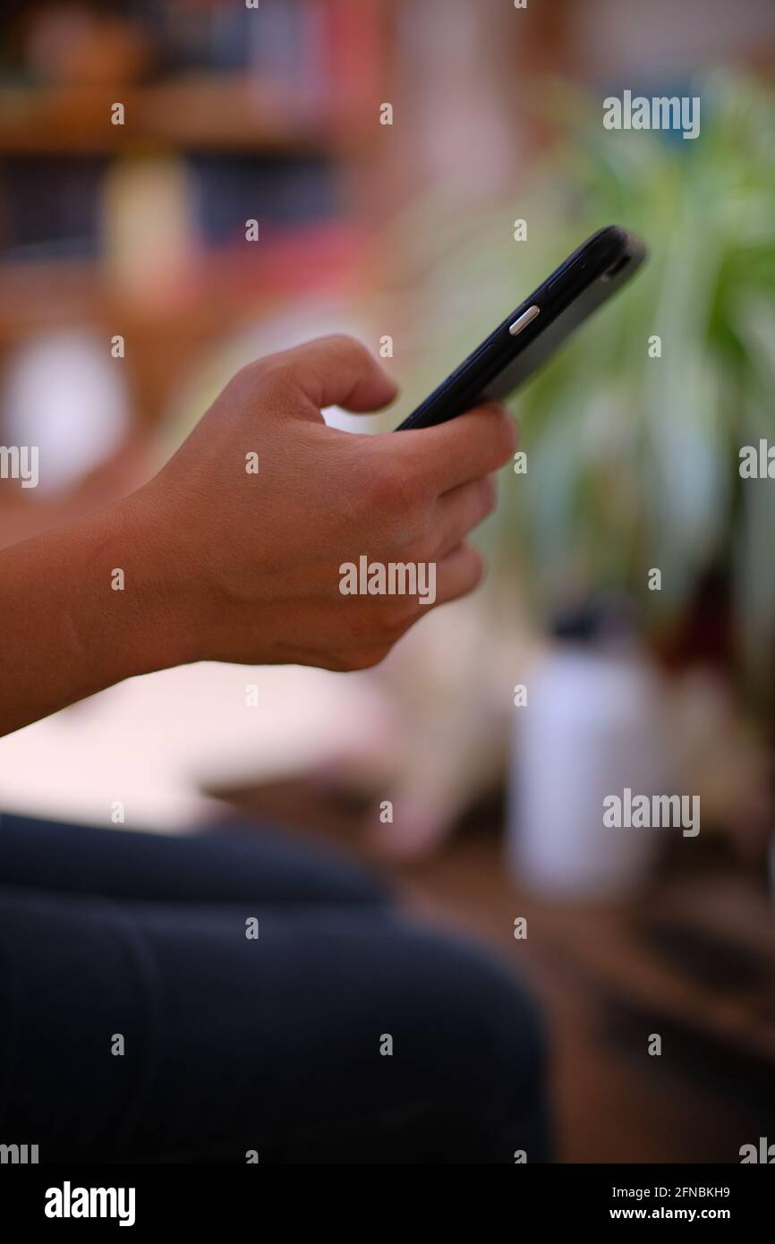 Fille ou femme philippine asiatique tenant un téléphone cellulaire et tapant avec son pouce à Cournonsec près de Montpellier, Occitanie, sud de la France Banque D'Images