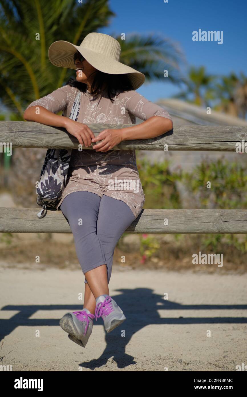 Femme asiatique, philippine portant un chapeau assis sur des poteaux de  clôture en bois au Parc du Levant, Palavas les Flots, près de Montpellier,  Occitanie, Sud de la France Photo Stock -