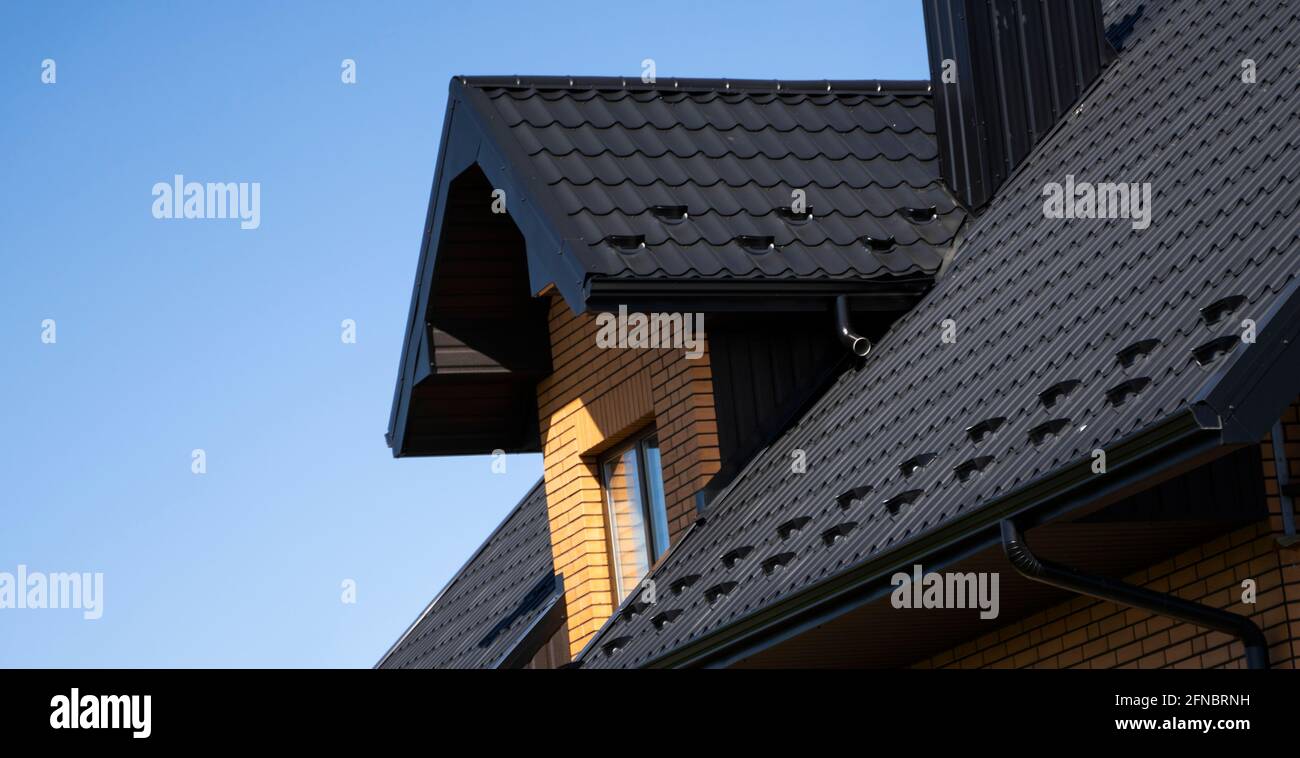 Toit en métal ondulé brun installé sur une maison moderne avec des fenêtres mansardées. Le toit de tôle ondulée. Toiture de profil métallique ondulée Banque D'Images