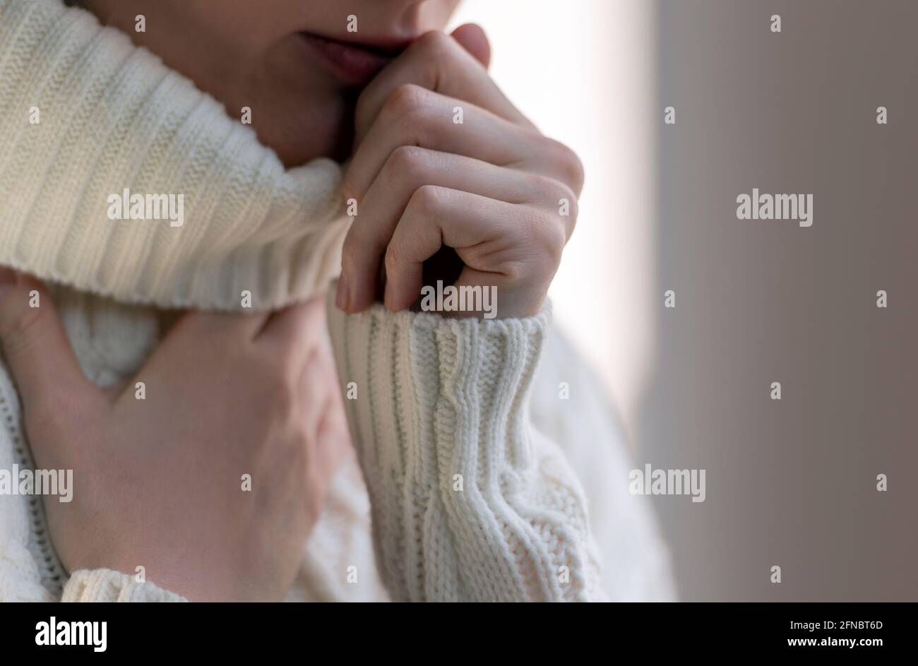 Une femme touchant la gorge avec de la toux et des maux de gorge. Femme malade avec la grippe en chandail blanc en hiver. Banque D'Images