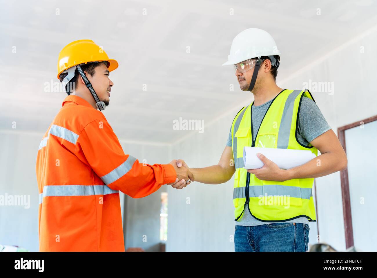 L'architecte et l'ingénieur asiatiques se sont mis en contact avec le contremaître après avoir donné des instructions sur le presse-papiers travaillant sur le chantier Banque D'Images