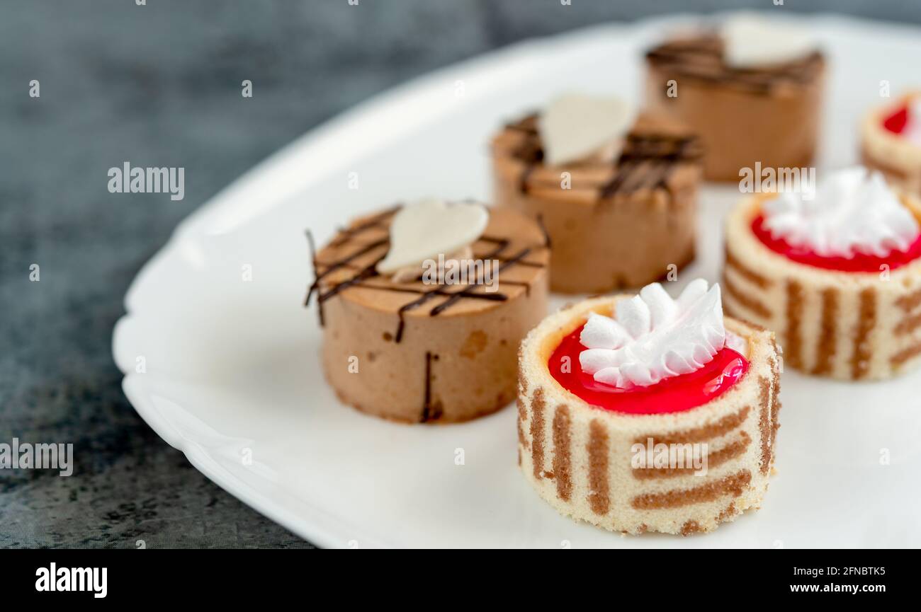 Ensemble de mini pâtisseries avec différentes garnitures sur une assiette plate, mise au point au premier plan Banque D'Images