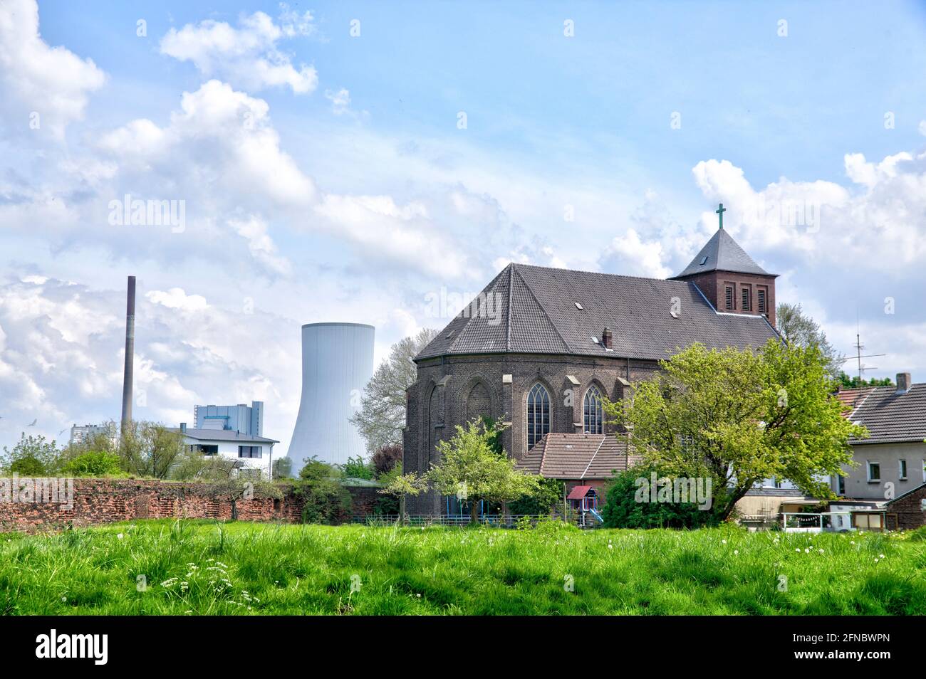 Die katholische Kirche St. Nikolaus in Rheinberg-Orsoy ist vor dem Kuehlturm des Kohlekraftwerks in Duisburg-Walsum zu sehen. Banque D'Images