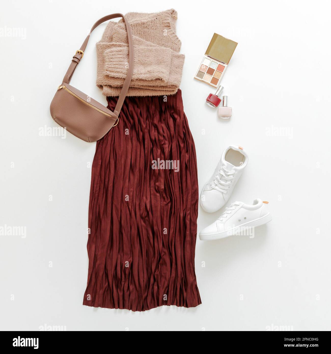 Vêtements pliés pour femme vêtements de base mode urbain. Femme look printemps tenue automne bordeaux jupe beige chandail blanc chaussures sac Sneakers, maquillage Banque D'Images