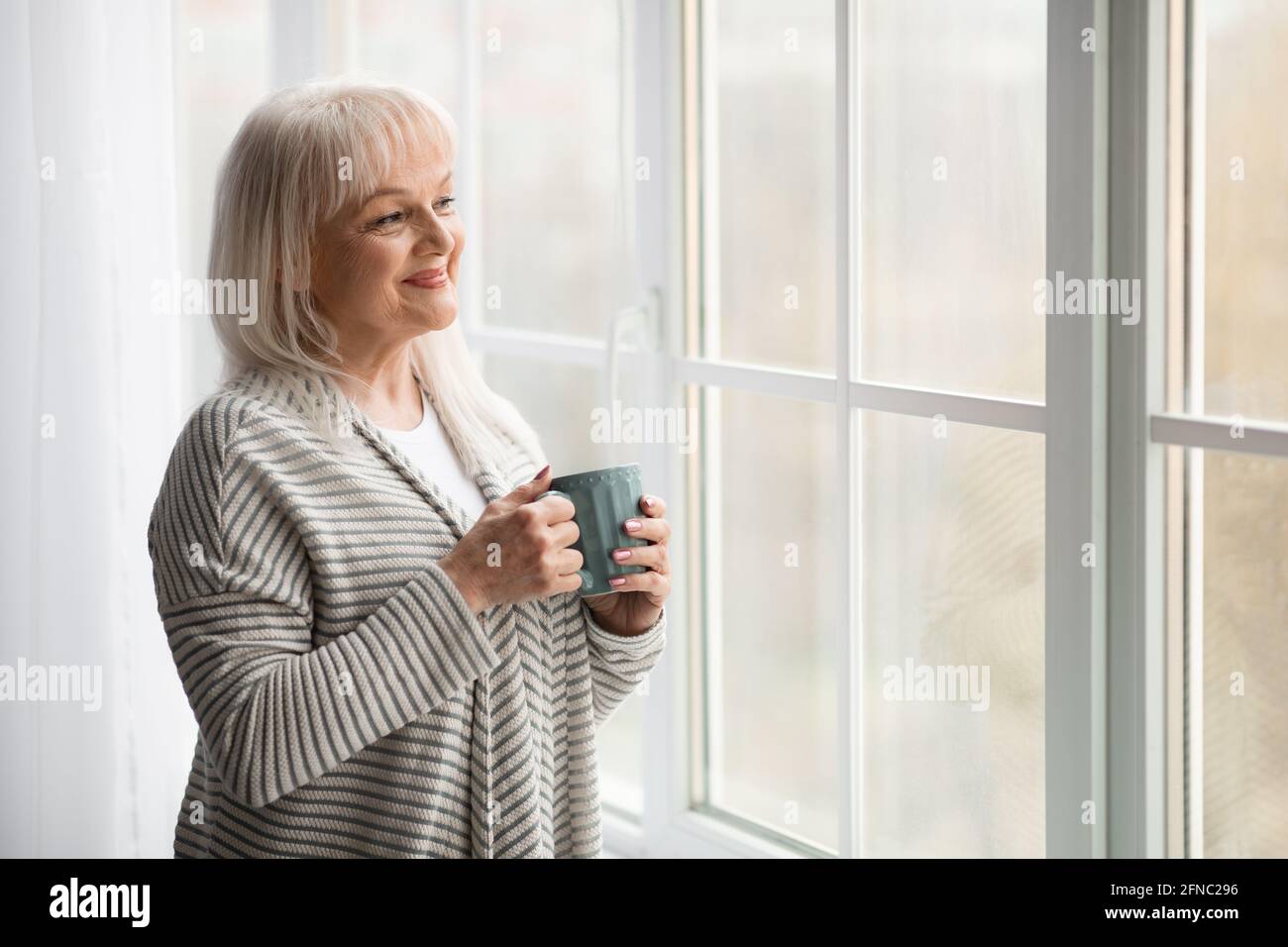 Portrait d'une femme mûre souriante qui boit du café chaud Banque D'Images