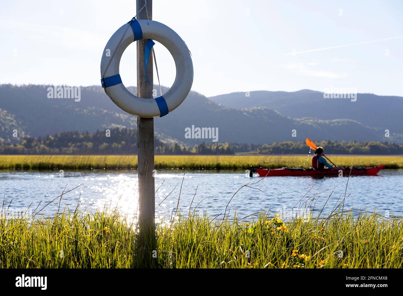 Femme kayak par une bouée de sauvetage sur un lac de baignade Banque D'Images