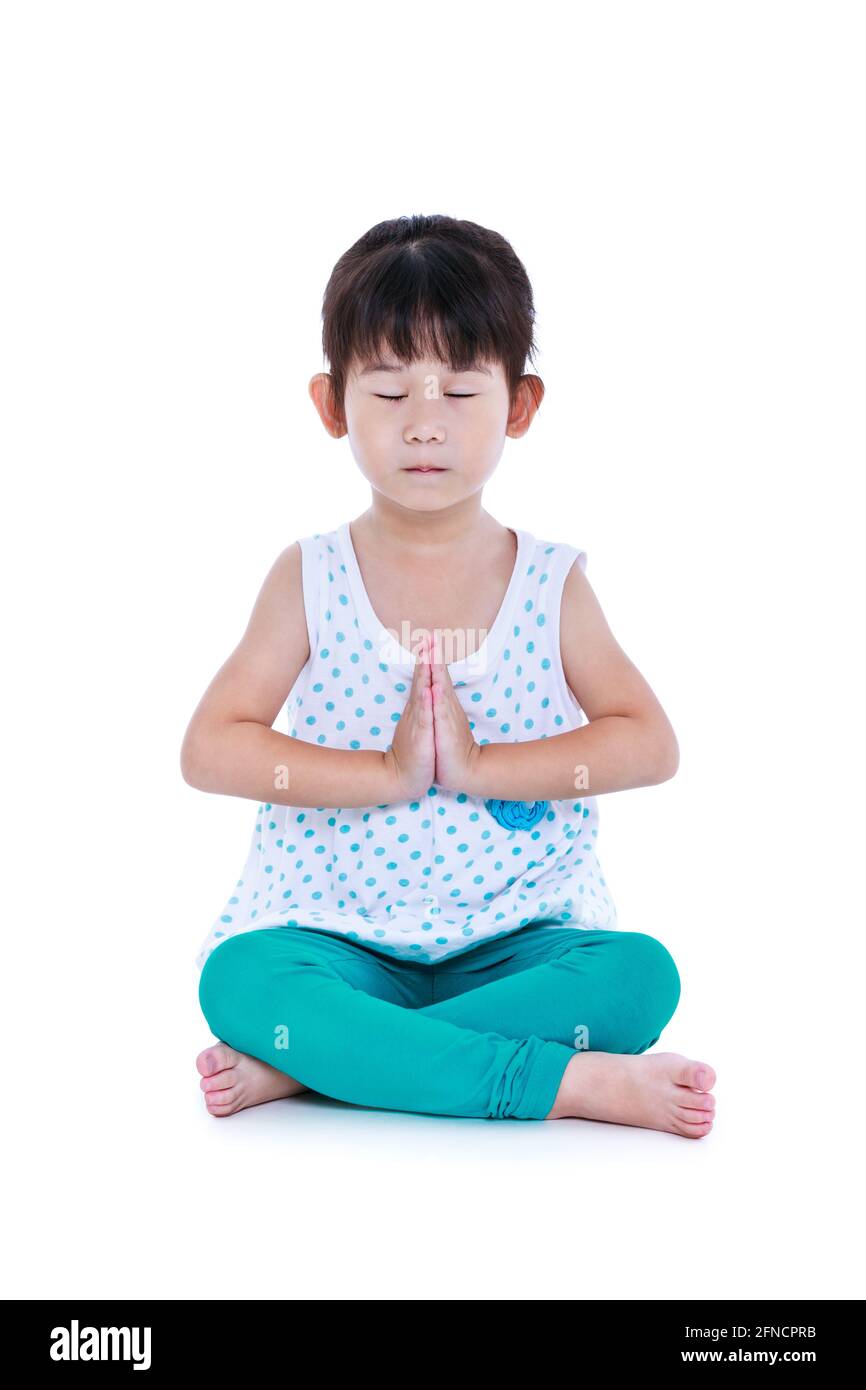 Enfant asiatique joli avec les yeux fermés et faisant des exercices de yoga dans la pose de lotus. Fille en bonne santé pratiquant la forme physique au studio. Isolé sur fond blanc. Banque D'Images