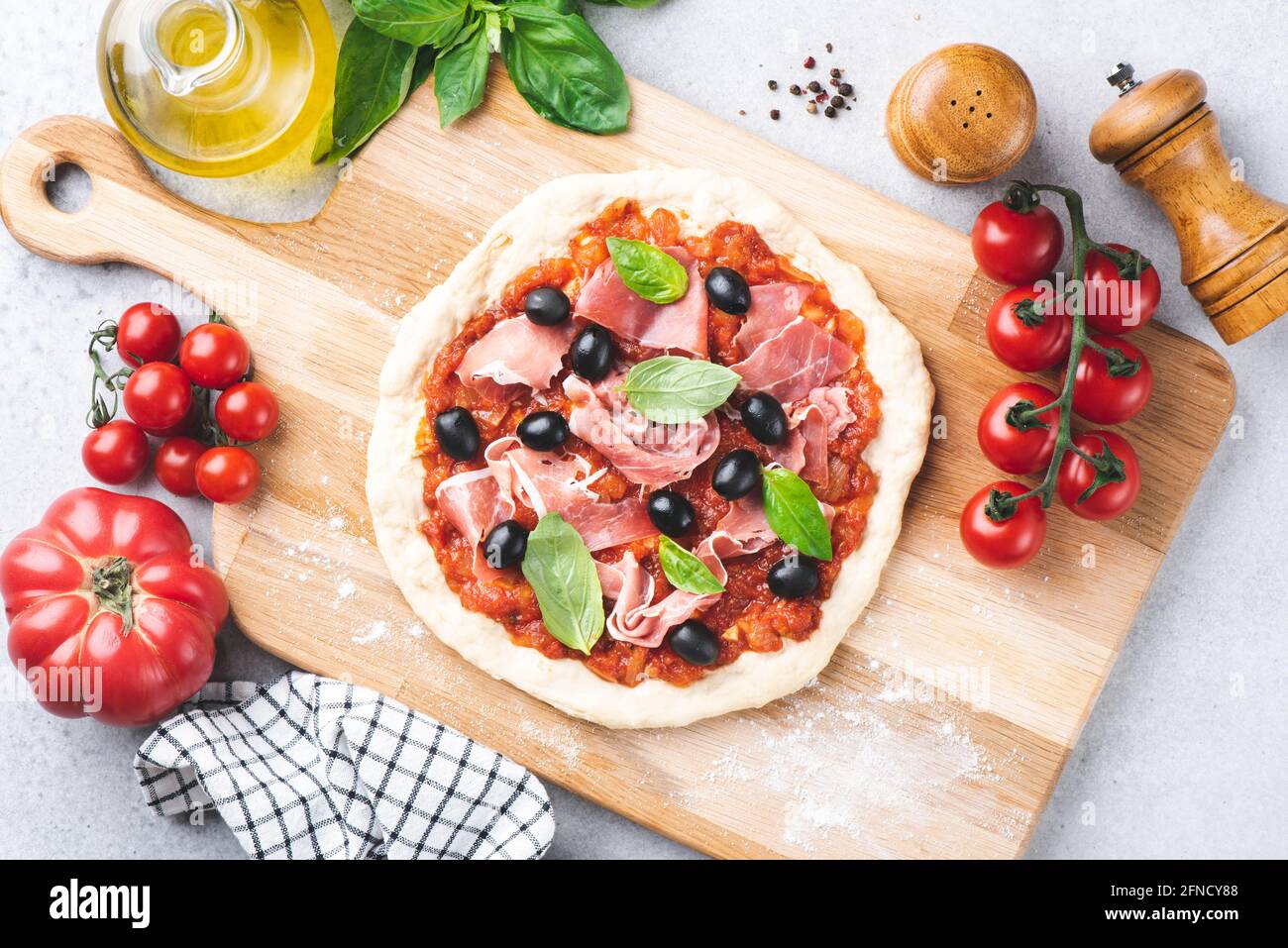 Pizza non cuite avec sauce tomate, prosciutto et olives sur fond de bois, vue sur le dessus. Faire cuire de la pizza à la maison Banque D'Images