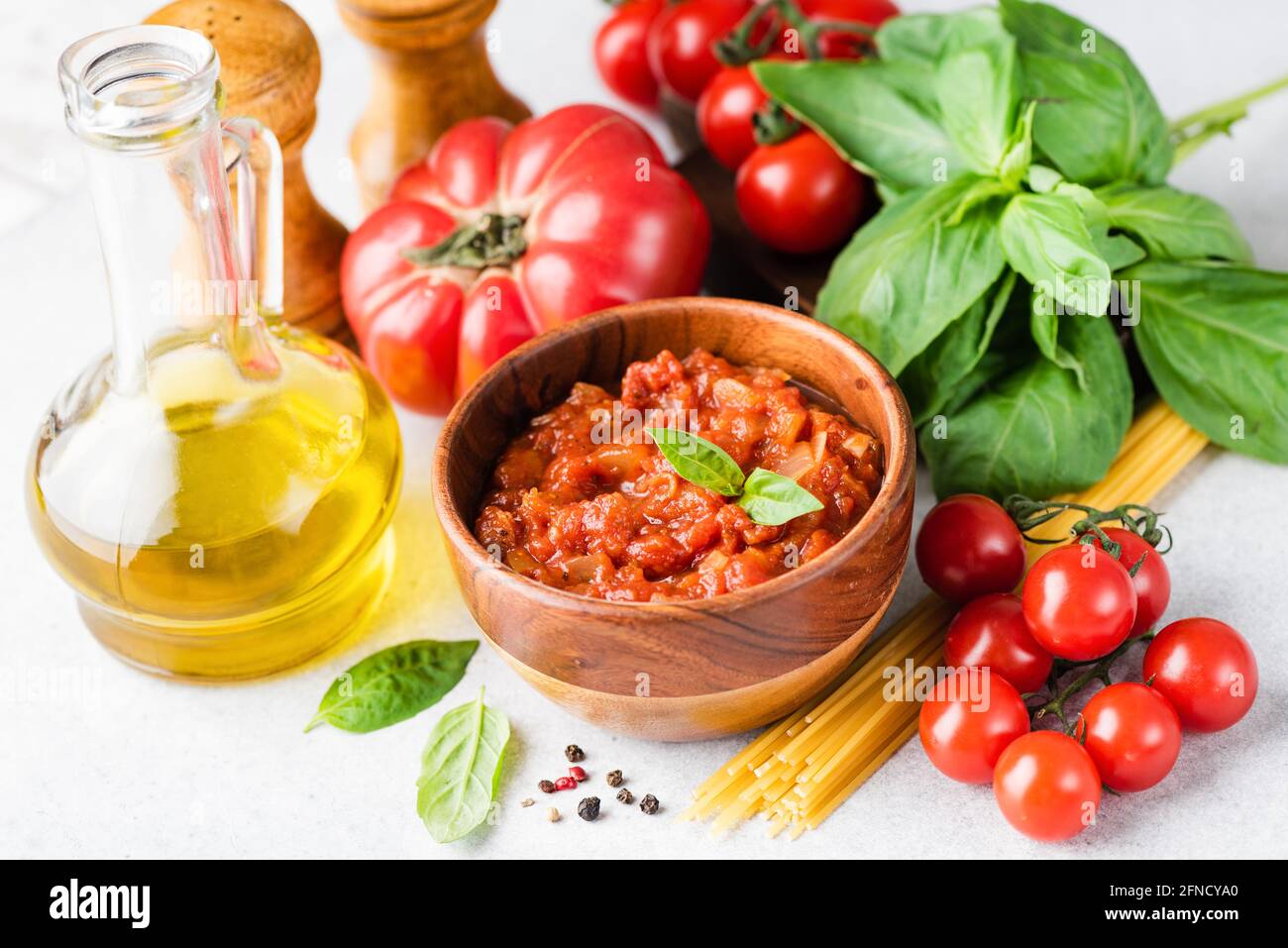 Sauce tomate Marinara, huile d'olive, pâtes non cuites, feuilles de basilic vert et tomates. Assortiment d'ingrédients alimentaires de cuisine italienne Banque D'Images