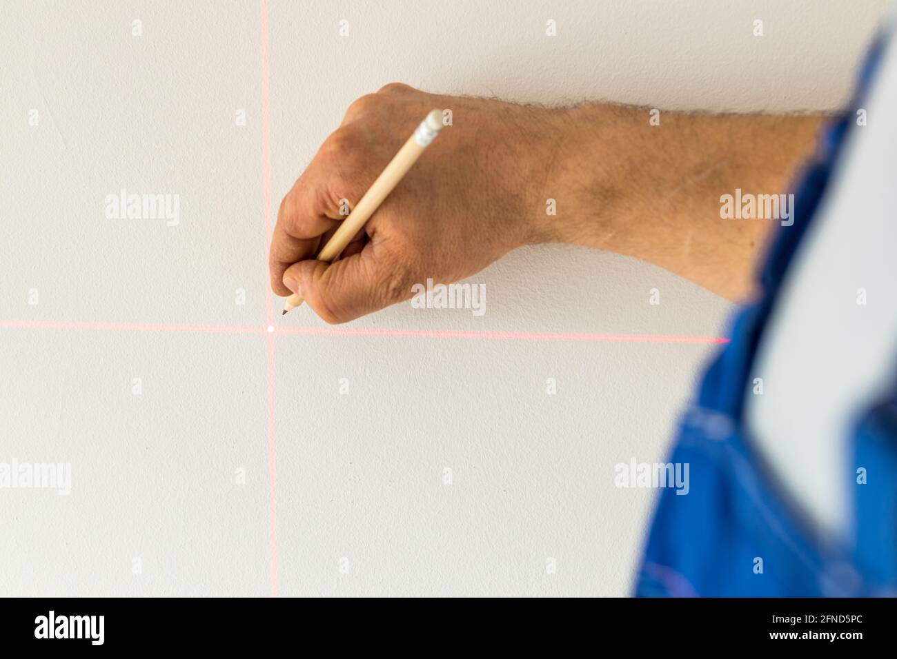 une personne qualifiée marque un point sur le mur marqué avec un laser électronique Banque D'Images