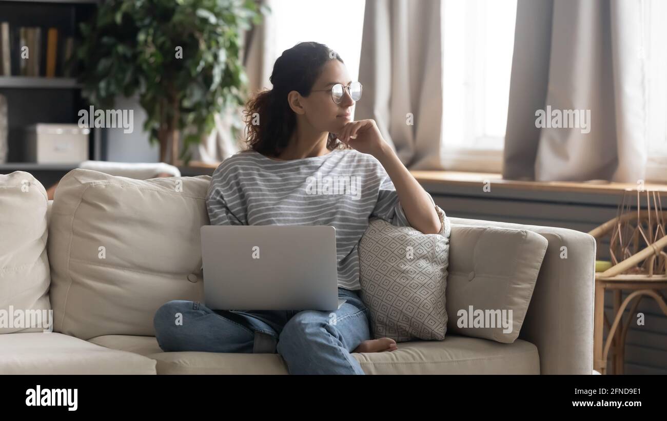 Une femme pensive travaille sur un ordinateur portable qui réfléchit Banque D'Images
