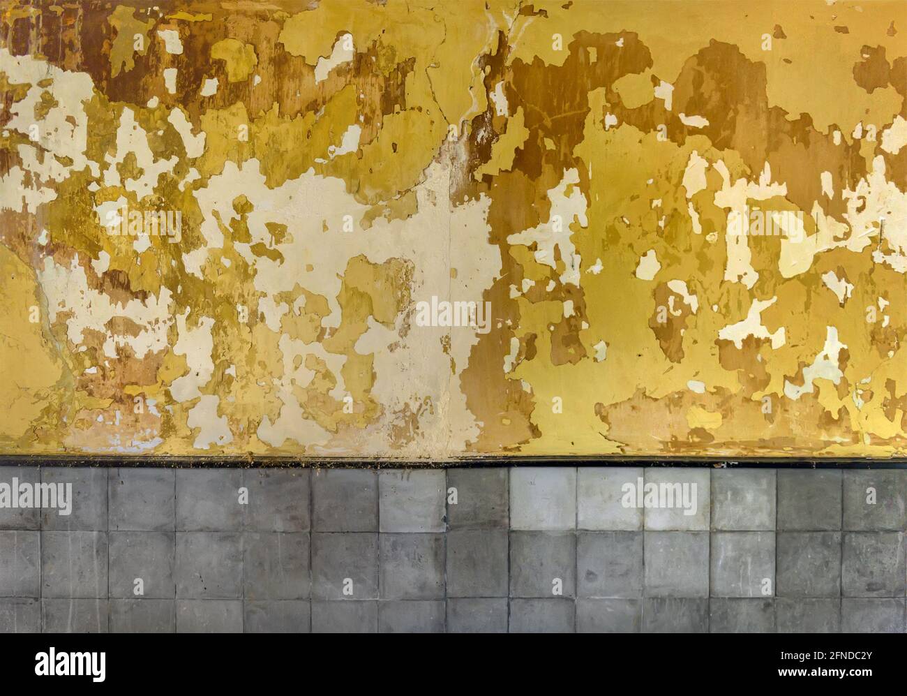 Texture de peinture écaillée. Grafez l'arrière-plan du mur avec de la peinture jaune craquelée et pelée et des carreaux gris Banque D'Images