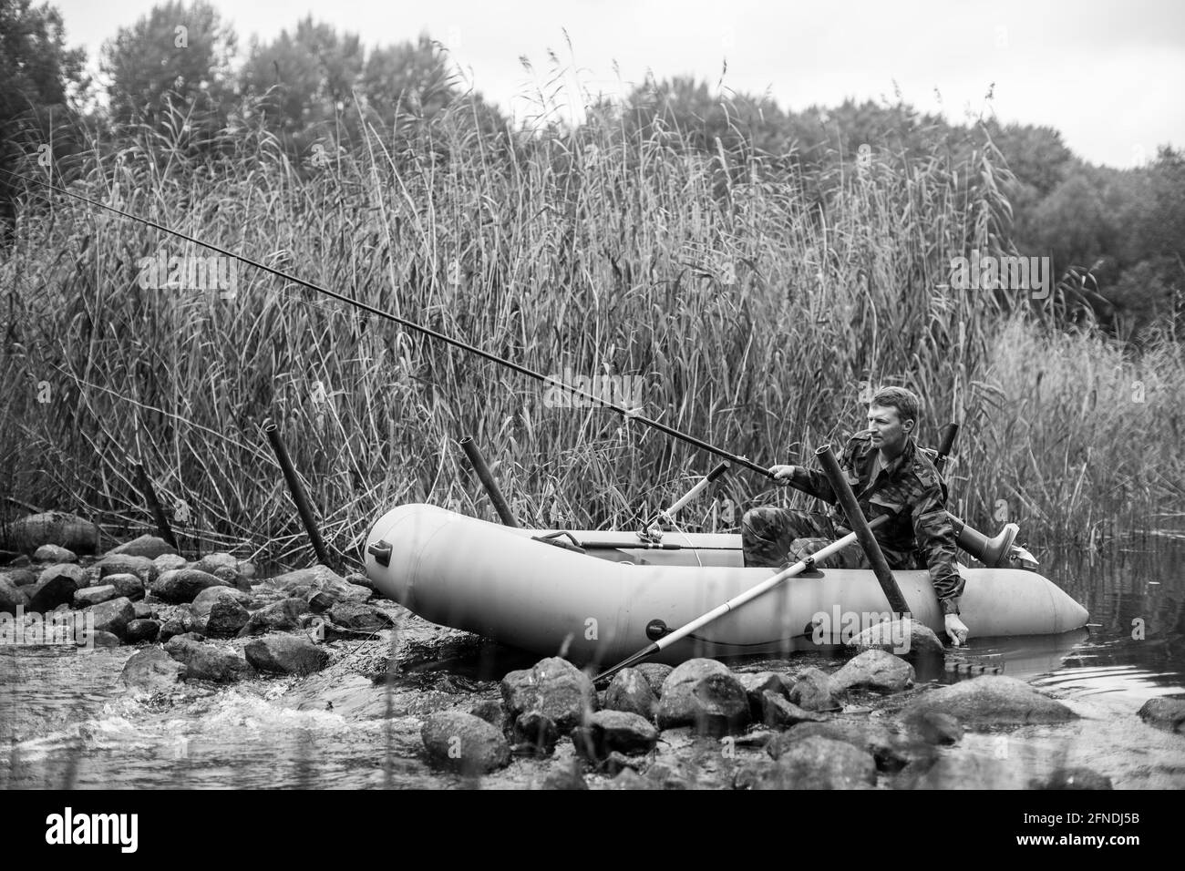 Vue sur un poisson de pêcheur sur la rivière sur un bateau en caoutchouc. Photo en noir et blanc. Banque D'Images