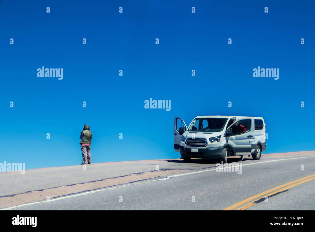 une femme se distingue par son bord de montagne route pendant que le mari est à la porte ouverte de la camionnette côté de la route Banque D'Images