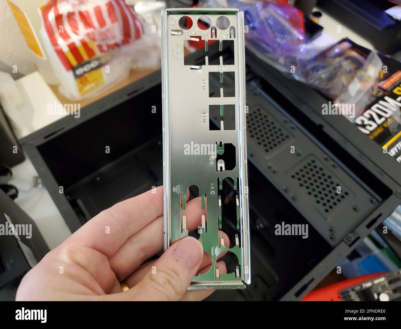 Photographie d'une personne tenant une plaque arrière d'E/S au-dessus d'un boîtier d'ordinateur de bureau ouvert à Lafayette, Californie, le 16 mars 2021. () Banque D'Images