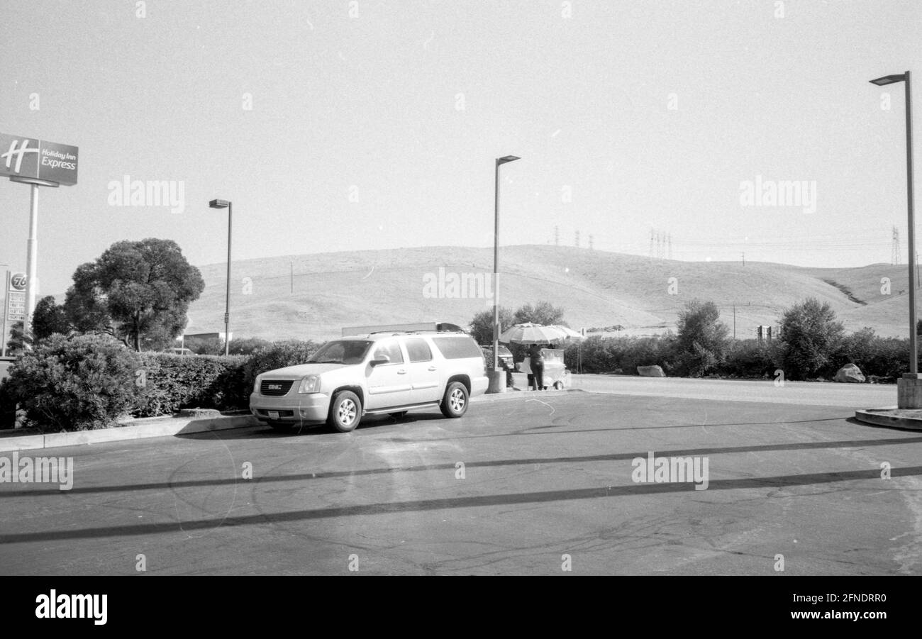 Photographie en noir et blanc d'un minibus avec un panneau annonçant le Holiday Inn Express et quelques montagnes en arrière-plan, le 15 août 2020. () Banque D'Images