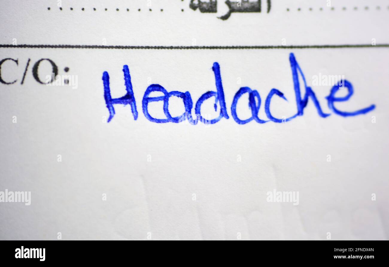 Le mot mal de tête qui est écrit à la main par un médecin sur un rapport d'hôpital, mal de tête est l'un des symptômes communs de nombreuses maladies dont le coron Banque D'Images
