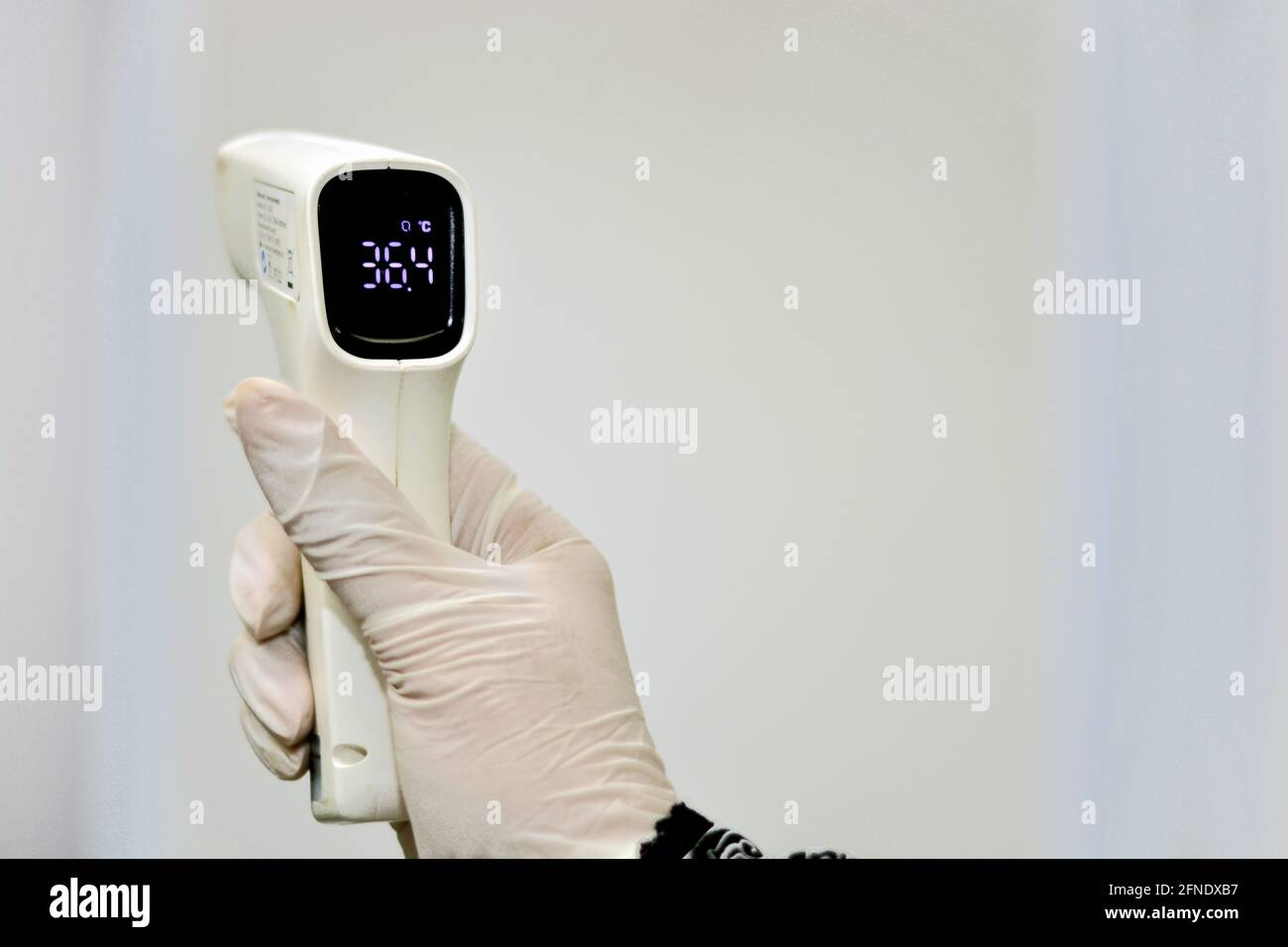 Thermomètre numérique frontal infrarouge sans contact tenu par un personnel médical qui vérifie la température du corps à la recherche de symptômes de virus Banque D'Images