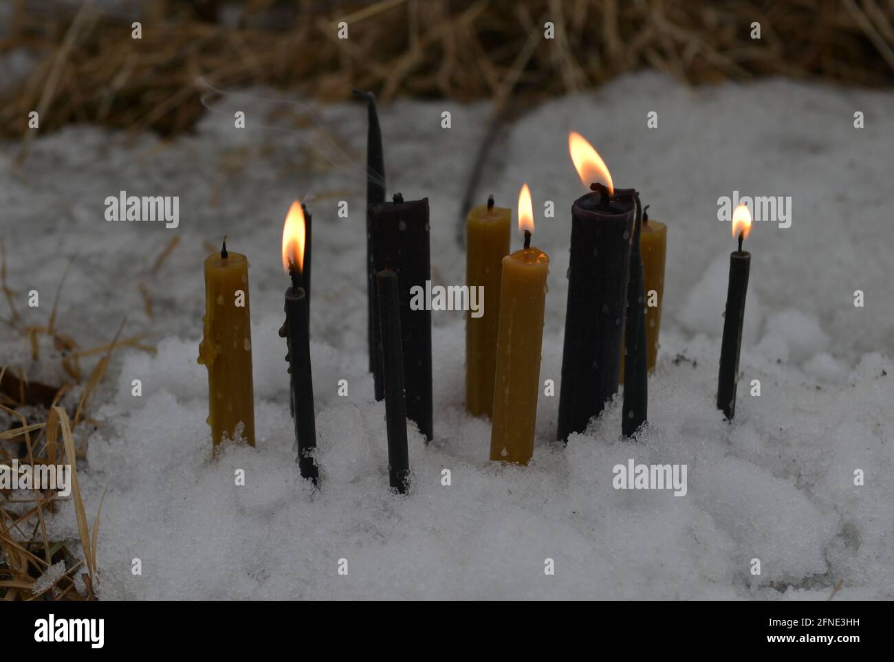 Toujours la vie avec des bougies allumées dans la neige dehors. Arrière-plan ésotérique, gothique et occulte, Halloween mystique et wicca concept en plein air. Banque D'Images