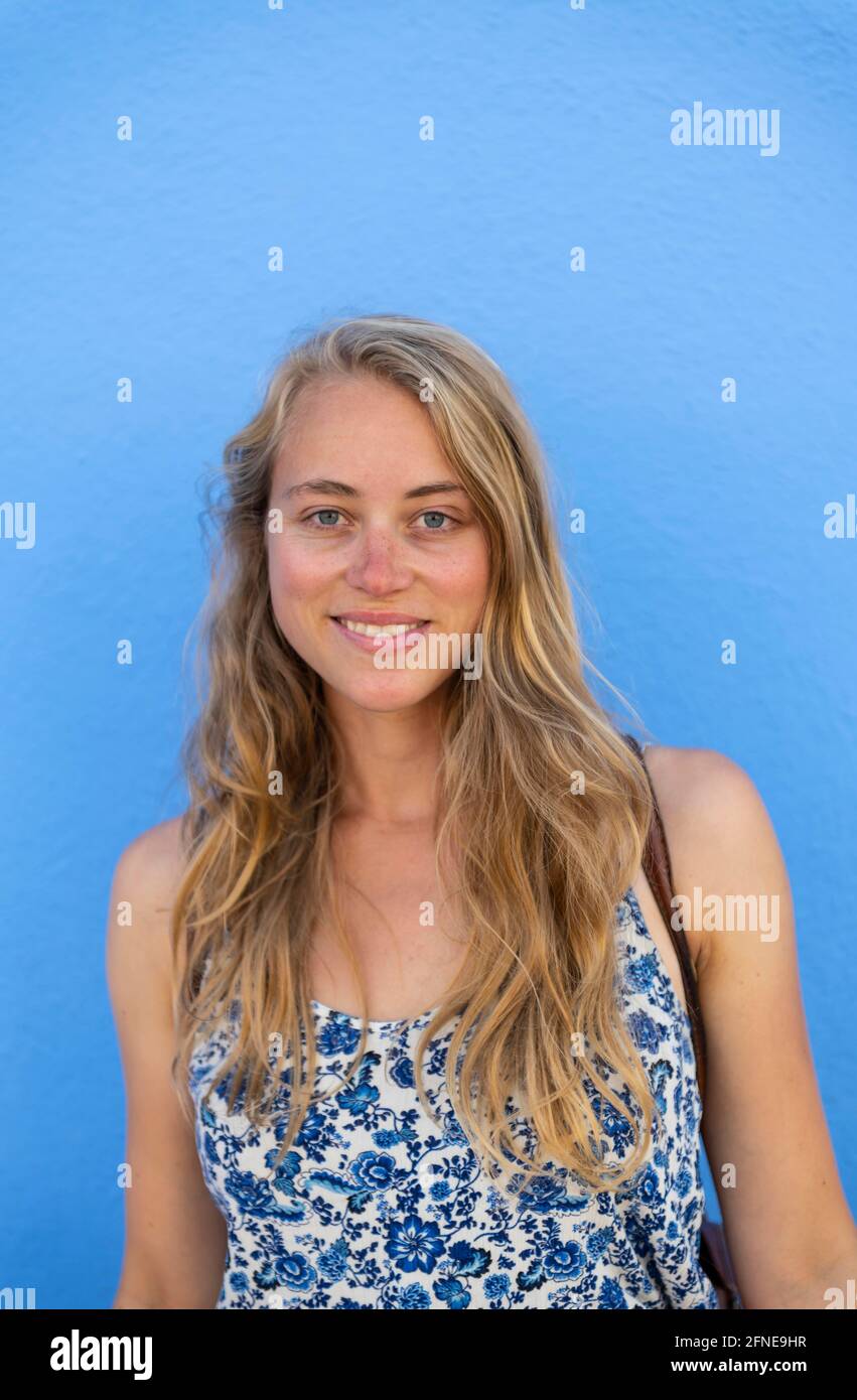 Portrait d'une jeune femme devant un mur bleu, île de Burano, Venise, Vénétie, Italie Banque D'Images