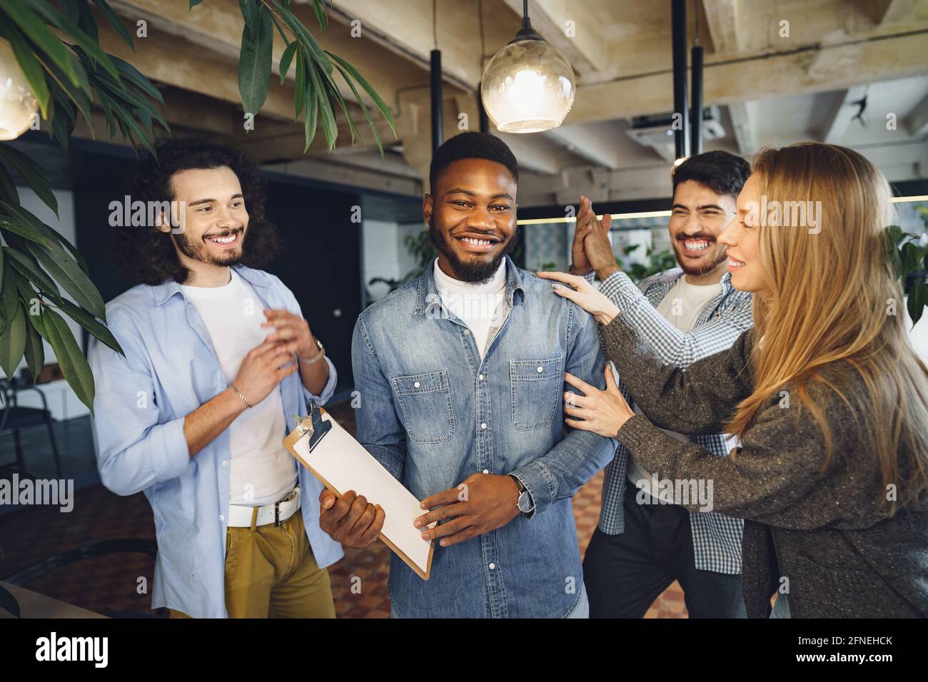 L'équipe de travail de bureau salue leur nouvel employé de sexe masculin afro-américain Banque D'Images