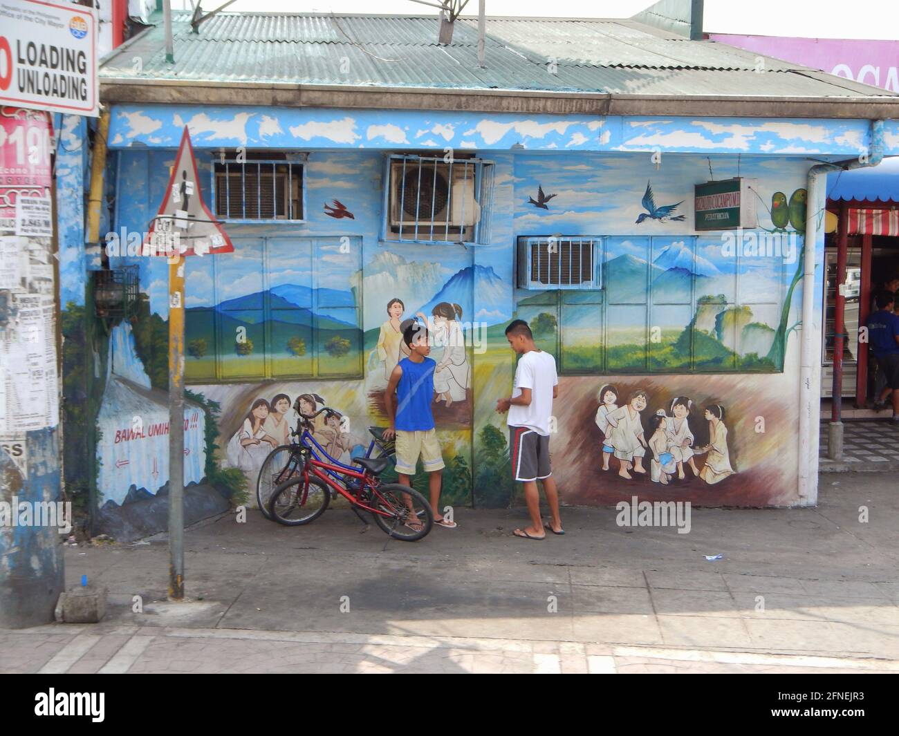 Garçons philippins discutant devant une fresque à Novaliches, Manille, Philippines Banque D'Images