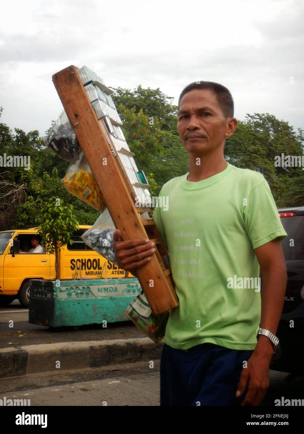 Jeune homme qui vend des cigarettes et des collations aux conducteurs de voiture sur une route à Novaliches, Manille, Philippines Banque D'Images