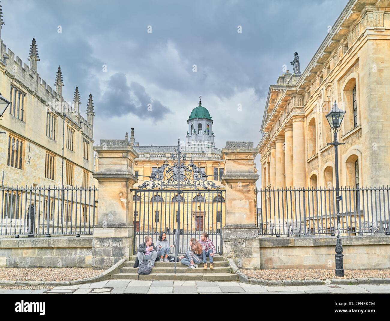 Quatre étudiants s'assoient et bavardent à l'extérieur de la bibliothèque Bodléienne d'Oxford (fermée en raison du Covid-19) avec le théâtre Sheldonian en arrière-plan. Banque D'Images