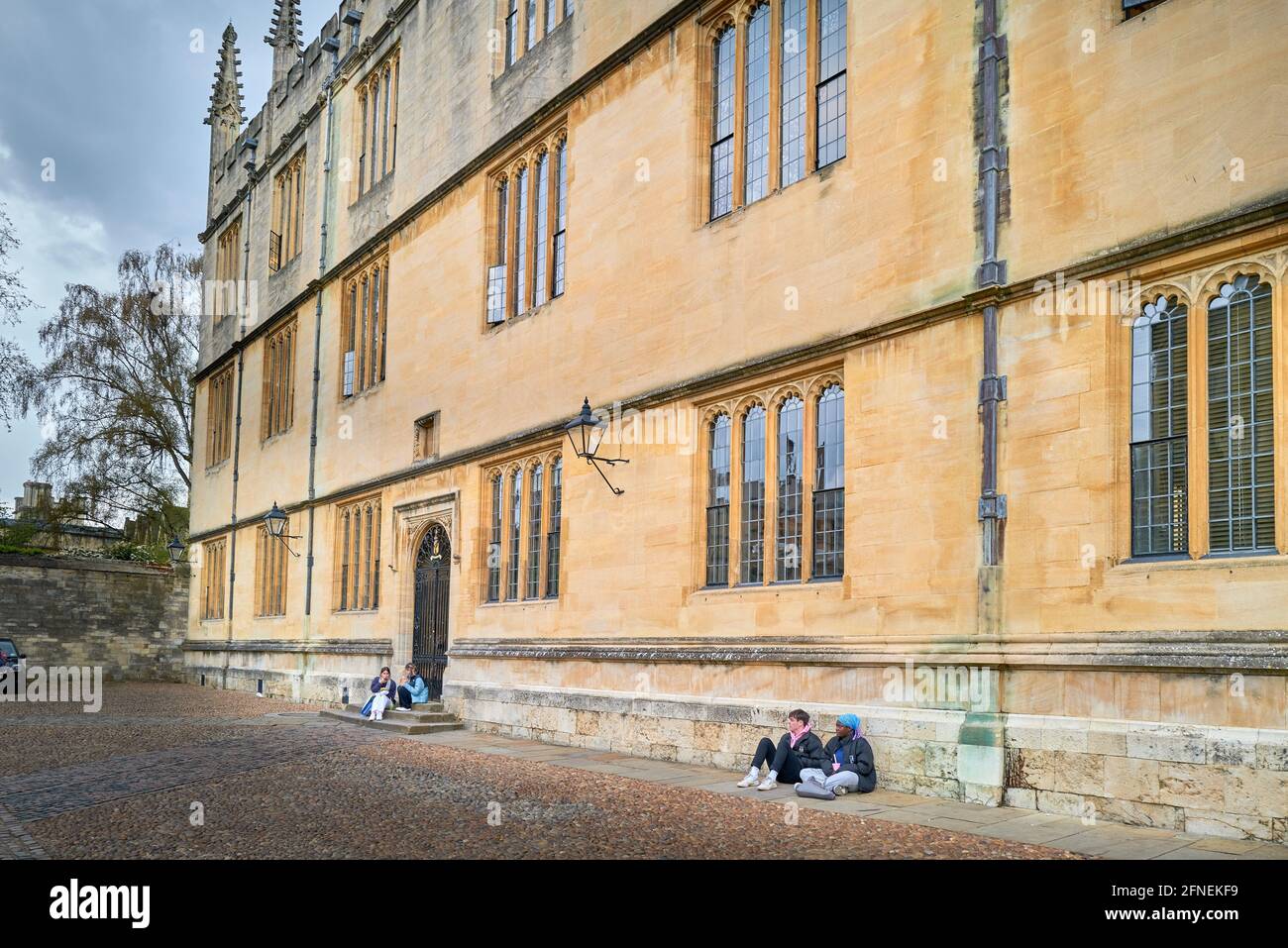 Les étudiants s'assoient contre le mur de l'université d'Oxford (Angleterre), la vieille bibliothèque bodléienne, qui est fermée en raison du Covid-19, mai 2021. Banque D'Images