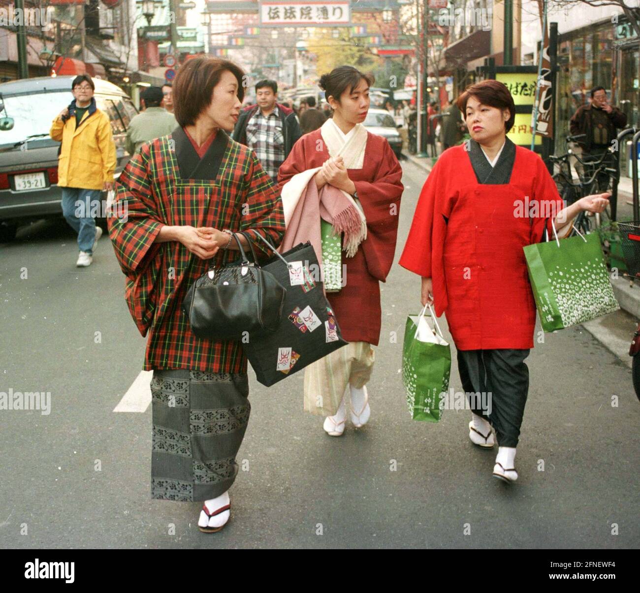 Trois femmes dans un kimono avec des sacs de shopping dans une rue commerçante du quartier d'Asakusa. [traduction automatique] Banque D'Images