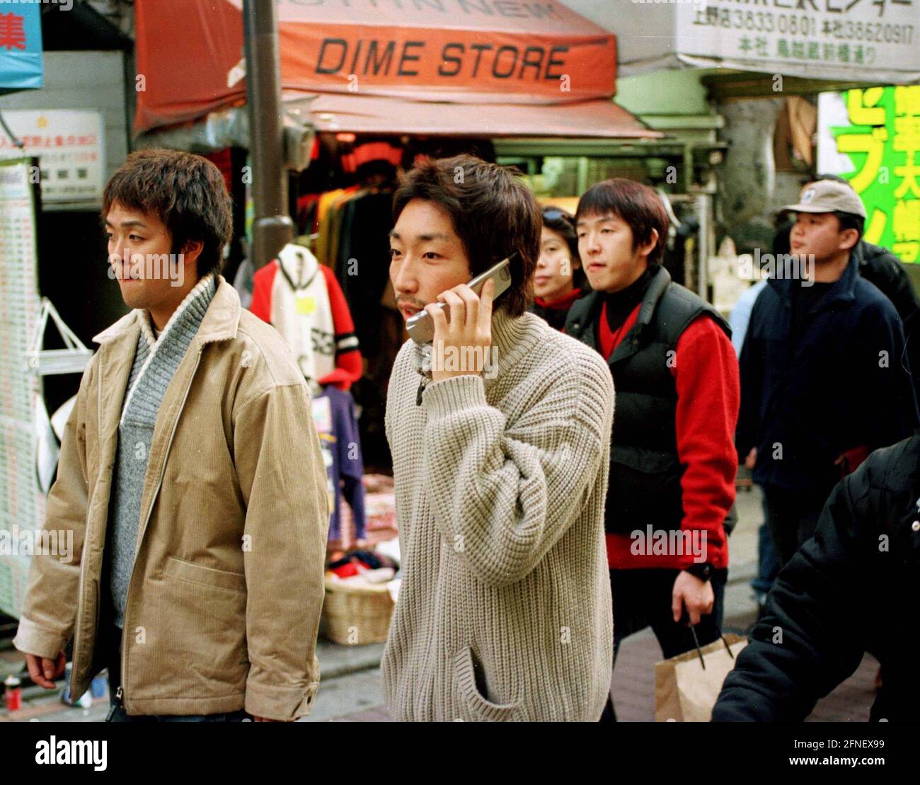 Piétons marchant dans une rue commerçante dans le quartier d'Ueno. Au premier plan un jeune homme avec un téléphone mobile parlant sur le téléphone. [traduction automatique] Banque D'Images